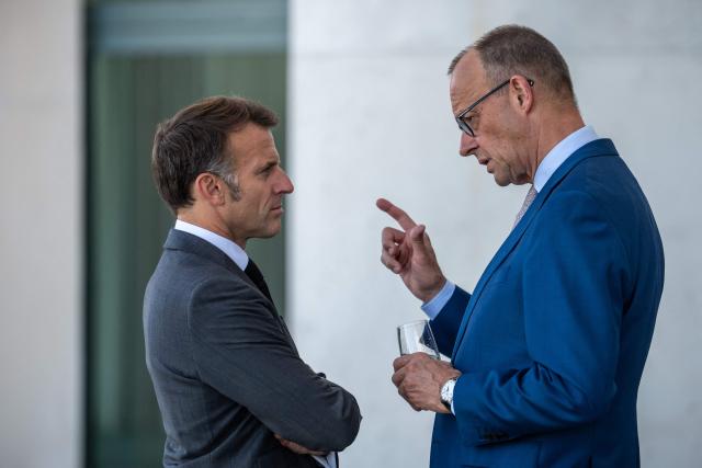 France's President Emmanuel Macron (L) and German Chancellor Friedrich Merz talk on a terrace of the Chancellery at the start of a meeting with state leaders of the European Group of Five (E5) and the NATO Secretary General on June 24, 2026 at the Chancellery in Berlin, Germany. (Photo by Michael Kappeler / POOL / AFP)