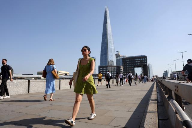 A person walks in the sun as they cross London Bridge, near the Shard skyscraper, during a heatwave, in central London on June 24, 2026. The UK recorded its hottest ever June temperature on Wednesday with the mercury rising to 35.7C south of London, breaking the previous record of 35.6C set in 1976. The UK's Met Office weather service said the temperature was recorded in Charlwood, near Gatwick Airport, as Britain experiences a second month in a row of record-breaking heat. (Photo by Toby Shepheard / AFP)