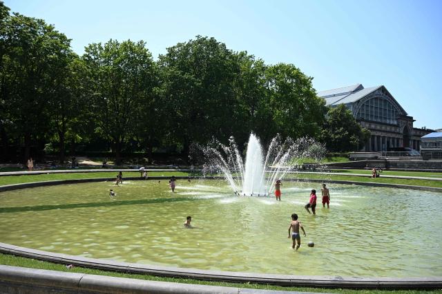Children play in the water of a fountain to refresh themselves during a heatwave, in Brussels on June 24, 2026. (Photo by Nicolas TUCAT / AFP)