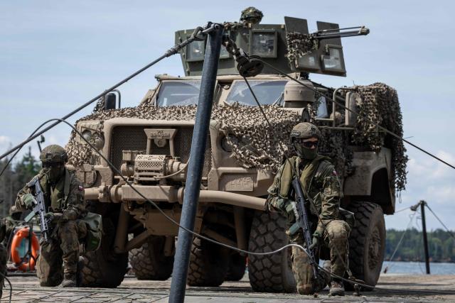 A Lithuanian Armed Forces US-made Oshkosh JLTV (Joint Light Tactical Vehicle) is seen on the deck of a Polish Army PFM Motorised Floating Bridge during a lake crossing as troops from Poland and Lithuania take part in the "Bursztynowy Obronca-26" (Amber Defender) military exercise on the Orzysz military training ground, north-eastern Poland, on June 24, 2026. (Photo by Wojtek RADWANSKI / AFP)
