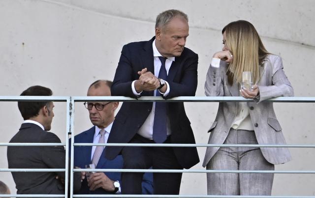 Italy's Prime Minister Giorgia Meloni (R) talks with Poland's Prime Minister Donald Tusk (2nd R) as in background can be seen German Chancellor Friedrich Merz talking with France's President Emmanuel Macron as they stand on a terrace of the Chancellery at the start of a meeting with state leaders of the European Group of Five (E5) and the NATO Secretary General on June 24, 2026 at the Chancellery in Berlin, Germany. (Photo by Tobias SCHWARZ / AFP)