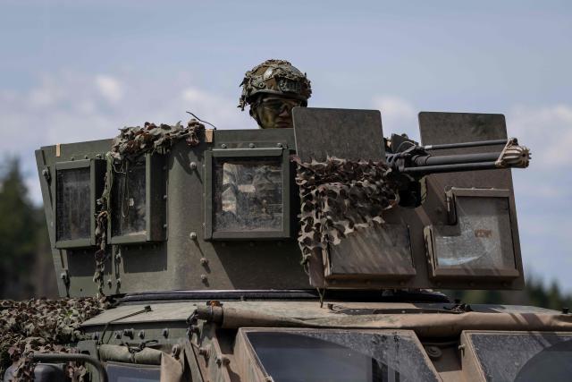 A Lithuanian soldier is seen behind a roof-mounted machine gun on a Lithuanian Armed Forces US-made Oshkosh JLTV (Joint Light Tactical Vehicle), on the deck of a Polish Army PFM Motorised Floating Bridge during a lake crossing, as troops from Poland and Lithuania take part in the "Bursztynowy Obronca-26" (Amber Defender) military exercise on the Orzysz military training ground, north-eastern Poland, on June 24, 2026. (Photo by Wojtek RADWANSKI / AFP)