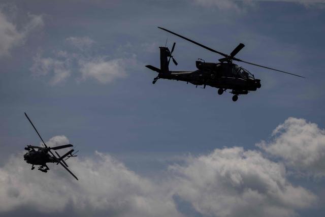 Two Polish Air Forces US-made AH-6h Apache helicopters participate in a lake crossing, as troops from Poland and Lithuania take part in the "Bursztynowy Obronca-26" (Amber Defender) military exercise on the Orzysz military training ground, north-eastern Poland, on June 24, 2026. (Photo by Wojtek RADWANSKI / AFP)