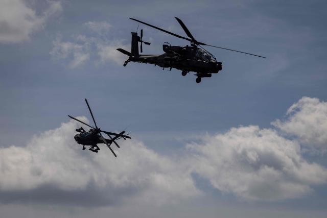 Two Polish Air Forces US-made AH-6h Apache helicopters participate in a lake crossing, as troops from Poland and Lithuania take part in the "Bursztynowy Obronca-26" (Amber Defender) military exercise on the Orzysz military training ground, north-eastern Poland, on June 24, 2026. (Photo by Wojtek RADWANSKI / AFP)