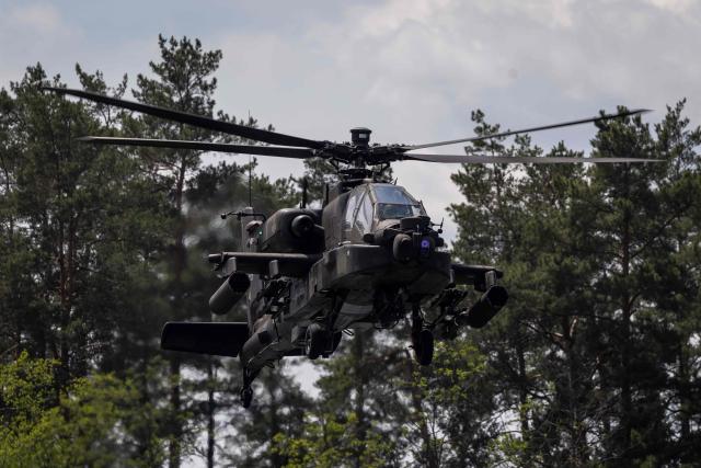 A Polish Air Forces US-made AH-6h Apache helicopter participates in a lake crossing, as troops from Poland and Lithuania take part in the "Bursztynowy Obronca-26" (Amber Defender) military exercise on the Orzysz military training ground, north-eastern Poland, on June 24, 2026. (Photo by Wojtek RADWANSKI / AFP)