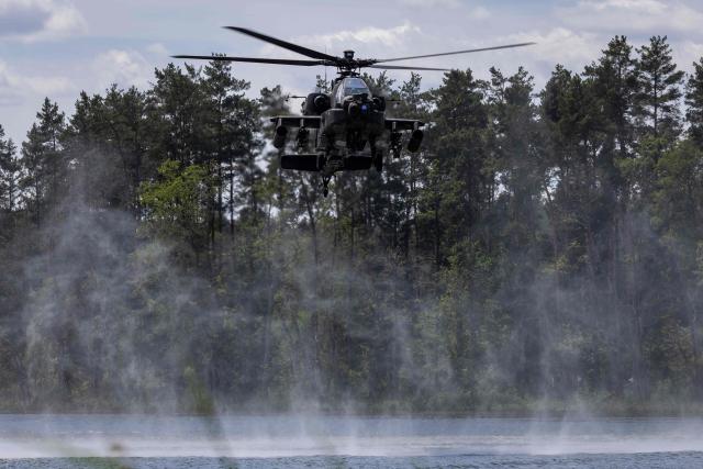 A Polish Air Forces US-made AH-6h Apache helicopter participates in a lake crossing, as troops from Poland and Lithuania take part in the "Bursztynowy Obronca-26" (Amber Defender) military exercise on the Orzysz military training ground, north-eastern Poland, on June 24, 2026. (Photo by Wojtek RADWANSKI / AFP)