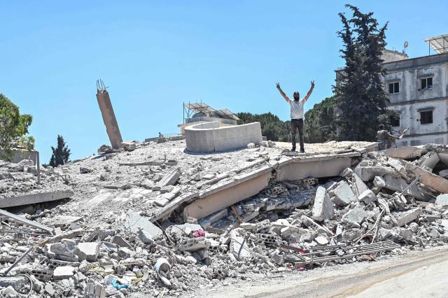 A resident flashes the V-sign for Victory as he stands on the roof of a collapsed home, destroyed in Israeli military strikes, in the southern Lebanese village of Srifa on June 24, 2026. Israeli Defence Minister said June 24, that the United States has not demanded that Israel withdraw its troops from southern Lebanon, a condition set by Lebanon in ongoing ceasefire negotiations. Lebanese President rejected Israel's occupation of the south and foreign interference in his country's affairs -- an allusion to Hezbollah's backer Iran -- as a fifth round of Israel-Lebanon talks began in Washington on June 23. (Photo by FADEL itani / AFP) / 