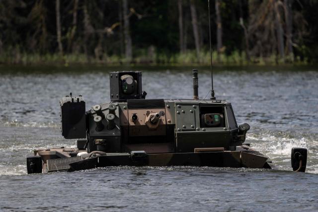 A Polish-made Borsuk amphibious Infantry Fighting Vehicle (IFV) crosses a lake, as troops from Poland and Lithuania take part in the "Bursztynowy Obronca-26" (Amber Defender) military exercise on the Orzysz military training ground, north-eastern Poland, on June 24, 2026. (Photo by Wojtek RADWANSKI / AFP)