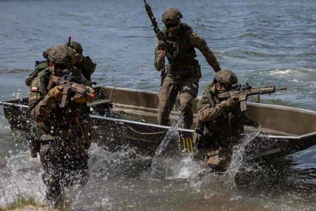 Polish soldiers disembark from a boat, as troops from Poland and Lithuania take part in the "Bursztynowy Obronca-26" (Amber Defender) military exercise on the Orzysz military training ground, north-eastern Poland, on June 24, 2026. (Photo by Wojtek RADWANSKI / AFP)