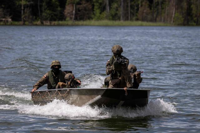 Polish soldiers cross a lake in a boat, as troops from Poland and Lithuania take part in the "Bursztynowy Obronca-26" (Amber Defender) military exercise on the Orzysz military training ground, north-eastern Poland, on June 24, 2026. (Photo by Wojtek RADWANSKI / AFP)