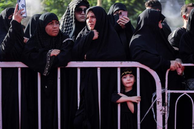 A girl stands with other women attending a Shia Muslim mourning procession outside the Shrine of Imam Hussein in Iraq's holy city of Karbala on June 24, 2026, coinciding with the the ninth day of the Muslim holy month of Muharram, the eve of Ashura (tenth day) which marks the seventh century killing of the Prophet Mohamed's grandson the Imam Hussein. (Photo by AHMAD AL-RUBAYE / AFP)