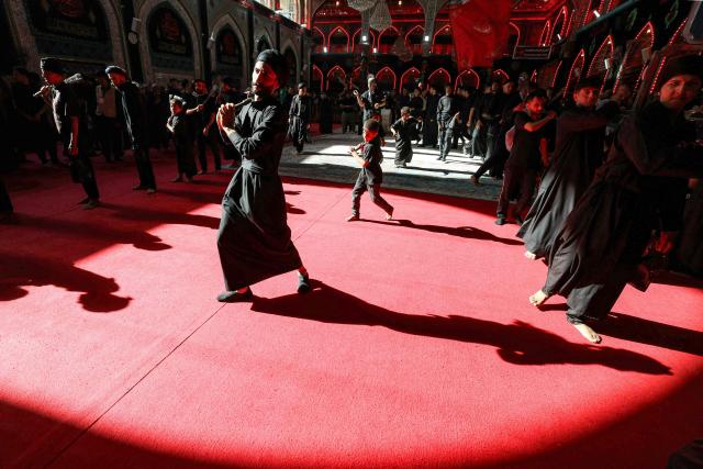 Shia Muslim devotees self-flagellate during a mourning procession at the Shrine of Imam Hussein in Iraq's holy city of Karbala on June 24, 2026, coinciding with the the ninth day of the Muslim holy month of Muharram, the eve of Ashura (tenth day) which marks the seventh century killing of the Prophet Mohamed's grandson the Imam Hussein. (Photo by AHMAD AL-RUBAYE / AFP)