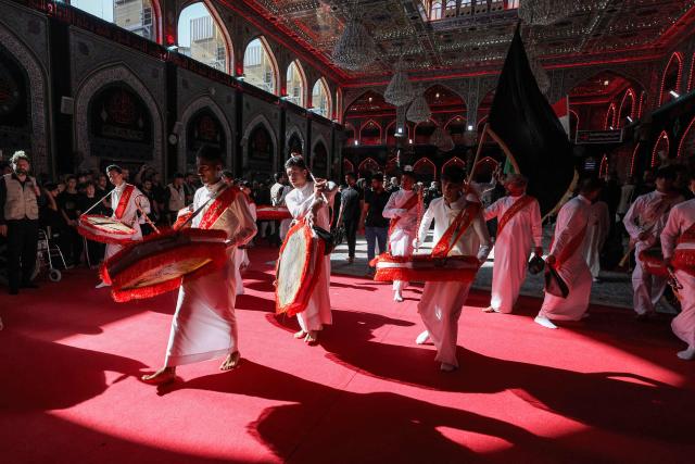 Men beat drums during a Shia Muslim mourning procession at the Shrine of Imam Hussein in Iraq's holy city of Karbala on June 24, 2026, coinciding with the the ninth day of the Muslim holy month of Muharram, the eve of Ashura (tenth day) which marks the seventh century killing of the Prophet Mohamed's grandson the Imam Hussein. (Photo by AHMAD AL-RUBAYE / AFP)
