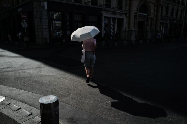 A woman walks under an umbrella to protect herself from the sun during a heatwave in Lyon, southern France, on June 24, 2026. More than 50 departments across mainland France recorded temperatures of 40C or higher since the latest heatwave began on June 17, an AFP analysis of weather data showed on June 24, 2026. Weather stations in 54 of mainland France's 96 departments recorded temperatures of 40C or higher from then until June 23, mainly in the west and south of the country, AFP found. (Photo by OLIVIER CHASSIGNOLE / AFP)
