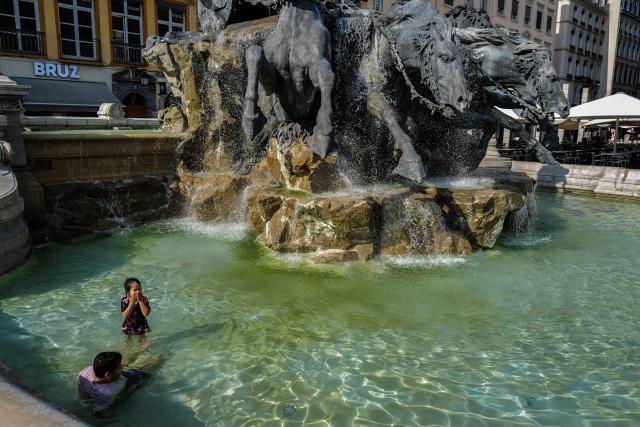 Children play in the water of a fountain during a heatwave in Lyon, southern France, on June 24, 2026. More than 50 departments across mainland France recorded temperatures of 40C or higher since the latest heatwave began on June 17, an AFP analysis of weather data showed on June 24, 2026. Weather stations in 54 of mainland France's 96 departments recorded temperatures of 40C or higher from then until June 23, mainly in the west and south of the country, AFP found. (Photo by OLIVIER CHASSIGNOLE / AFP)