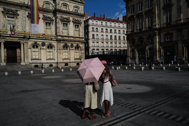 Two pedestrians stand under an umbrella during a heatwave in Lyon, southern France, on June 24, 2026. More than 50 departments across mainland France recorded temperatures of 40C or higher since the latest heatwave began on June 17, an AFP analysis of weather data showed on June 24, 2026. Weather stations in 54 of mainland France's 96 departments recorded temperatures of 40C or higher from then until June 23, mainly in the west and south of the country, AFP found. (Photo by OLIVIER CHASSIGNOLE / AFP)