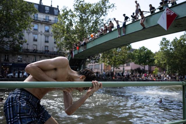 Youths jump into the Canal Saint-Martin during a heatwave in Paris in Paris on June 24, 2026. France experienced its hottest day ever recorded on June 24, 2026, surpassing the record set the previous day, according to national weather service Meteo-France. (Photo by Simon WOHLFAHRT / AFP)