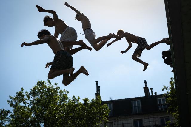 Youths jump into the Canal Saint-Martin during a heatwave in Paris in Paris on June 24, 2026. France experienced its hottest day ever recorded on June 24, 2026, surpassing the record set the previous day, according to national weather service Meteo-France. (Photo by Simon WOHLFAHRT / AFP)
