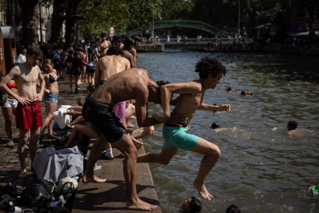 Youths jump into the Canal Saint-Martin during a heatwave in Paris in Paris on June 24, 2026. France experienced its hottest day ever recorded on June 24, 2026, surpassing the record set the previous day, according to national weather service Meteo-France. (Photo by Simon WOHLFAHRT / AFP)