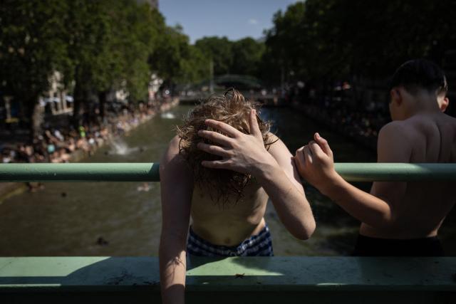 a young kid takes his head in his hand before jumping into the Canal Saint-Martin during a heatwave in Paris in Paris on June 24, 2026. France experienced its hottest day ever recorded on June 24, 2026, surpassing the record set the previous day, according to national weather service Meteo-France. (Photo by Simon WOHLFAHRT / AFP)