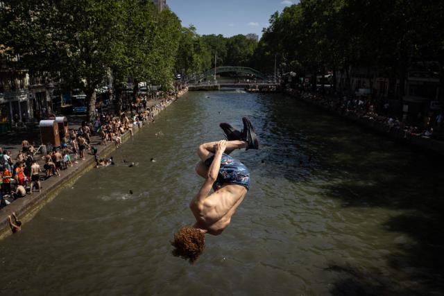 Youths jump into the Canal Saint-Martin during a heatwave in Paris in Paris on June 24, 2026. France experienced its hottest day ever recorded on June 24, 2026, surpassing the record set the previous day, according to national weather service Meteo-France. (Photo by Simon WOHLFAHRT / AFP)