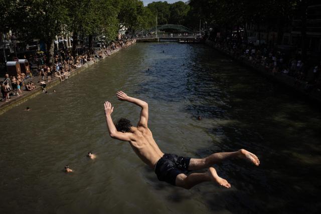Youths jump into the Canal Saint-Martin during a heatwave in Paris in Paris on June 24, 2026. France experienced its hottest day ever recorded on June 24, 2026, surpassing the record set the previous day, according to national weather service Meteo-France. (Photo by Simon WOHLFAHRT / AFP)