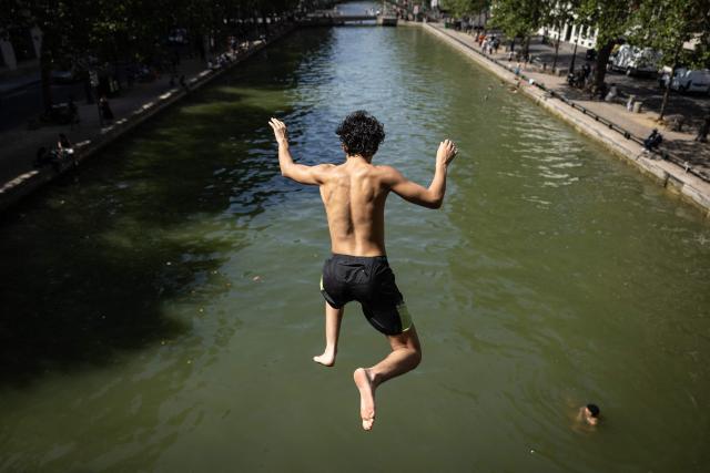 Youths jump into the Canal Saint-Martin during a heatwave in Paris in Paris on June 24, 2026. France experienced its hottest day ever recorded on June 24, 2026, surpassing the record set the previous day, according to national weather service Meteo-France. (Photo by Simon WOHLFAHRT / AFP)