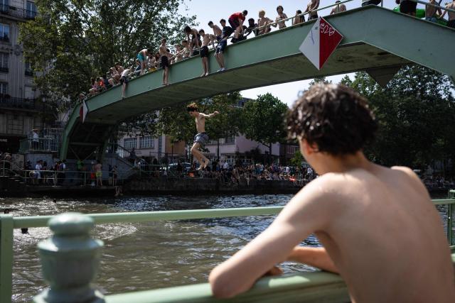 Youths jump into the Canal Saint-Martin during a heatwave in Paris in Paris on June 24, 2026. France experienced its hottest day ever recorded on June 24, 2026, surpassing the record set the previous day, according to national weather service Meteo-France. (Photo by Simon WOHLFAHRT / AFP)