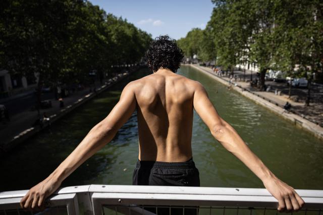 Youths jump into the Canal Saint-Martin during a heatwave in Paris in Paris on June 24, 2026. France experienced its hottest day ever recorded on June 24, 2026, surpassing the record set the previous day, according to national weather service Meteo-France. (Photo by Simon WOHLFAHRT / AFP)