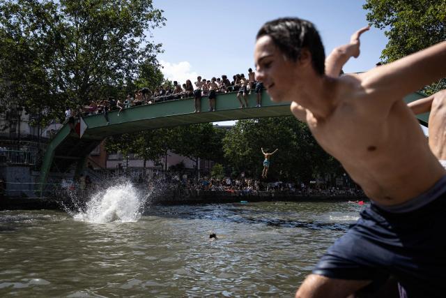 Youths jump into the Canal Saint-Martin during a heatwave in Paris in Paris on June 24, 2026. France experienced its hottest day ever recorded on June 24, 2026, surpassing the record set the previous day, according to national weather service Meteo-France. (Photo by Simon WOHLFAHRT / AFP)