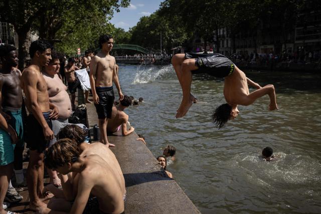 Youths jump into the Canal Saint-Martin during a heatwave in Paris in Paris on June 24, 2026. France experienced its hottest day ever recorded on June 24, 2026, surpassing the record set the previous day, according to national weather service Meteo-France. (Photo by Simon WOHLFAHRT / AFP)