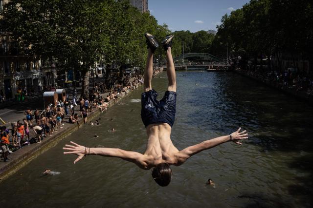 Youths jump into the Canal Saint-Martin during a heatwave in Paris in Paris on June 24, 2026. France experienced its hottest day ever recorded on June 24, 2026, surpassing the record set the previous day, according to national weather service Meteo-France. (Photo by Simon WOHLFAHRT / AFP)