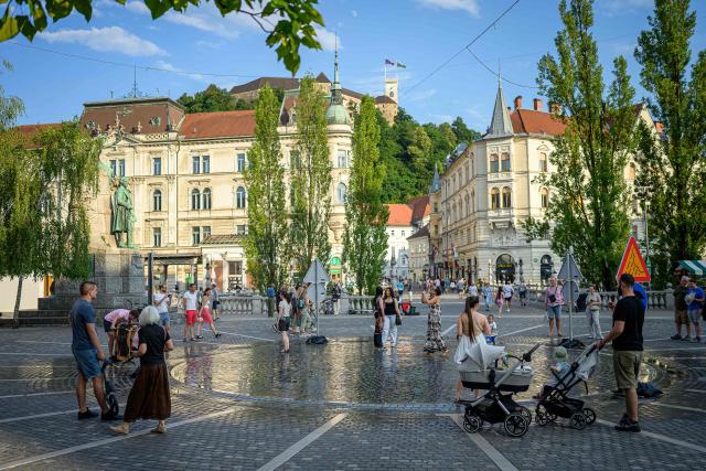 Pedestrians cool off at “The area with Ljubljana’s own weather” in Preseren Square in Ljubljana on June 24, 2026. Europe struggled to cope with a record-breaking heatwave on June 24, 2026, with at least 94 million people expected to experience temperatures above 35C, most of them in France and Spain. (Photo by Jure MAKOVEC / AFP)