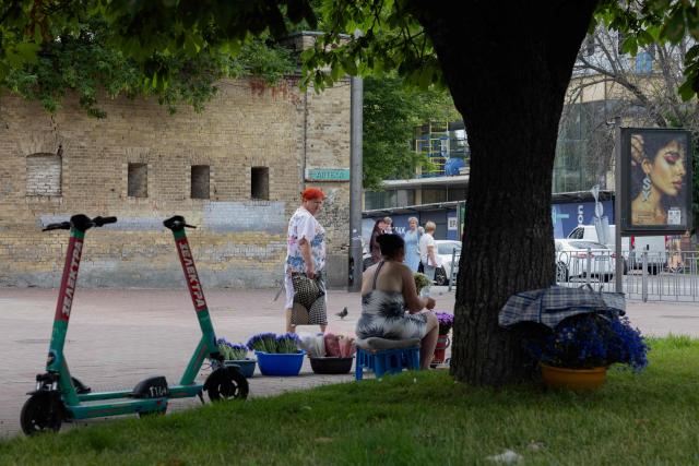 A woman looks at a flower seller in Kyiv on June 24, 2026, amid the Russian invasion of Ukraine. (Photo by Tetiana DZHAFAROVA / AFP)