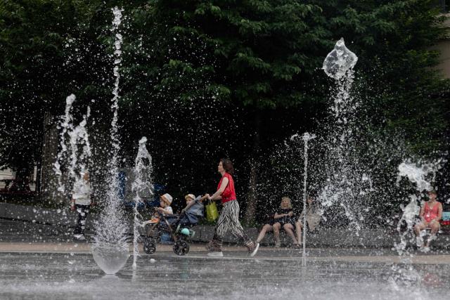 A woman walks with a stroller near a fountain in Kyiv on June 24, 2026, amid the Russian invasion of Ukraine. Europe struggled to cope with a record-breaking heatwave on June 24, 2026, with at least 94 million people expected to experience temperatures above 35C, most of them in France and Spain. (Photo by Tetiana DZHAFAROVA / AFP)