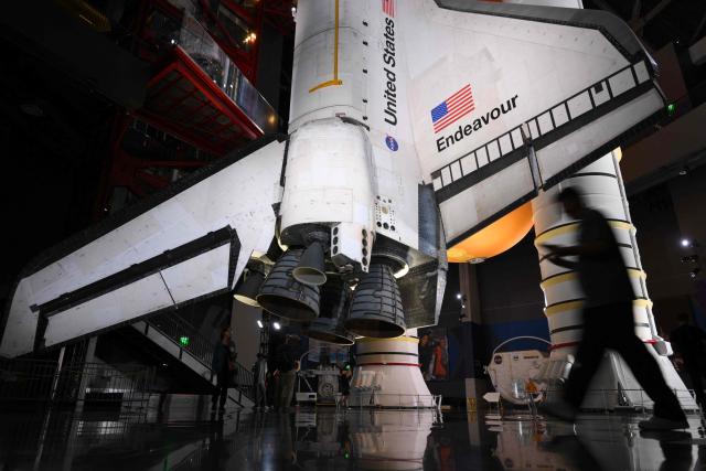 People take pictures underneath NASA’s Space Shuttle Endeavour as it stands stacked complete in a launch-ready vertical display with the ET-94 External Fuel Tank and a pair of Solid Rocket Boosters (SRBs) inside the Samuel Oschin Shuttle Gallery at the California Science Center in Los Angeles, on June 24, 2026. The Space Shuttle Endeavour exhibit will open on November 13, 2026 as part of a 200,000-square-foot expansion with the Samuel Oschin Air and Space Center. (Photo by Patrick T. Fallon / AFP)