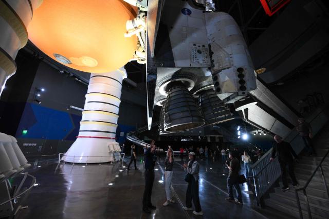 People take pictures underneath NASA’s Space Shuttle Endeavour as it stands stacked complete in a launch-ready vertical display with the ET-94 External Fuel Tank and a pair of Solid Rocket Boosters (SRBs) inside the Samuel Oschin Shuttle Gallery at the California Science Center in Los Angeles, on June 24, 2026. The Space Shuttle Endeavour exhibit will open on November 13, 2026 as part of a 200,000-square-foot expansion with the Samuel Oschin Air and Space Center. (Photo by Patrick T. Fallon / AFP)