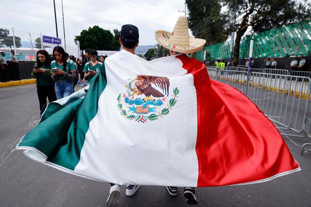 Mexican fans wrapped in a national flag arrive at the Mexico City Stadium ahead of the 2026 World Cup Group A football match between the Czech Republic and Mexico in Mexico City on June 24, 2026.  (Photo by Rodrigo Oropeza / AFP)