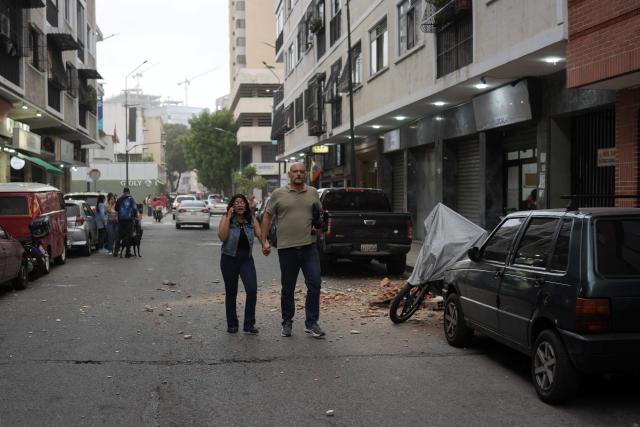 People remain on a street following an earthquake in Caracas on June 24, 2026. A magnitude 7.1 earthquake struck Venezuela on Wednesday, the United States Geological Survey (USGS) reported, triggering panic in Caracas, according to AFP journalists. The tremor, which was followed by several aftershocks, was also felt in Colombia. (Photo by Manaure QUINTERO / AFP)