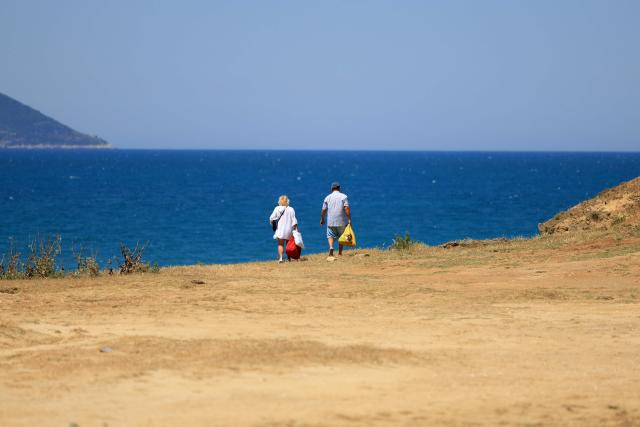 Tourists make their way down to one of the beaches of Zvernec, near Vlora on June 18, 2026. (Photo by Adnan Beci / AFP)