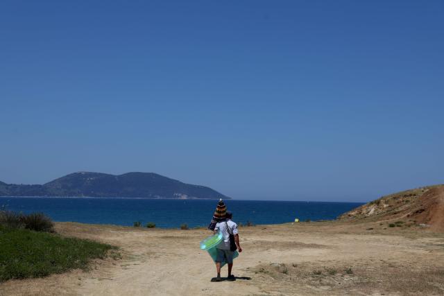 Tourists make their way down to one of the beaches of Zvernec, near Vlora on June 18, 2026. (Photo by Adnan Beci / AFP)