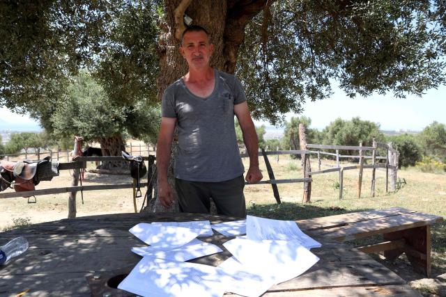 Gentian Mocka, 56, a resident of Novosele and one of the claimed landowners in Zvernec, poses in front of documents he possesses at his horse farm, in Vlora on June 18, 2026. (Photo by Adnan Beci / AFP)