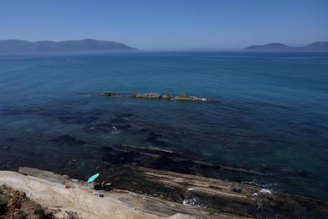Tourists stand on a beach in Zvernec, near Vlora on June 18, 2026. (Photo by Adnan Beci / AFP)