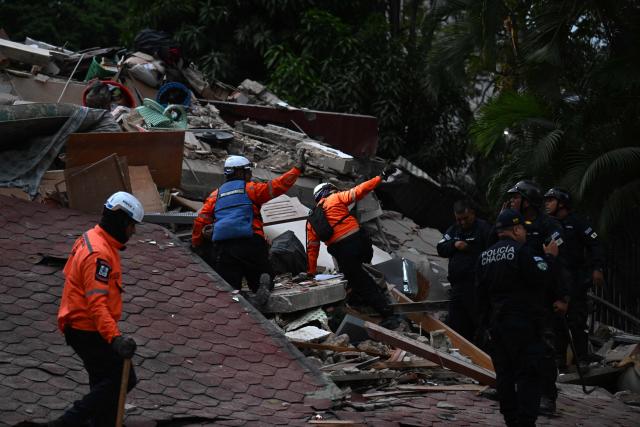 Rescue workers search through the remains of a collapsed structure as municipal police officers stand nearby following an earthquake in Caracas on June 24, 2026. A magnitude 7.1 earthquake struck Venezuela on Wednesday, the United States Geological Survey (USGS) reported, triggering panic in Caracas, according to AFP journalists. The tremor, which was followed by several aftershocks, was also felt in Colombia. (Photo by Juan BARRETO / AFP)