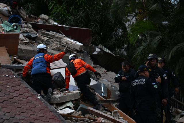 Rescue workers search through the remains of a collapsed structure as municipal police officers stand nearby following an earthquake in Caracas on June 24, 2026. A magnitude 7.1 earthquake struck Venezuela on Wednesday, the United States Geological Survey (USGS) reported, triggering panic in Caracas, according to AFP journalists. The tremor, which was followed by several aftershocks, was also felt in Colombia. (Photo by Juan BARRETO / AFP)