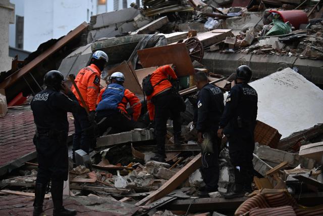Rescue workers search through the remains of a collapsed structure as municipal police officers stand nearby following an earthquake in Caracas on June 24, 2026. A magnitude 7.1 earthquake struck Venezuela on Wednesday, the United States Geological Survey (USGS) reported, triggering panic in Caracas, according to AFP journalists. The tremor, which was followed by several aftershocks, was also felt in Colombia. (Photo by Juan BARRETO / AFP)