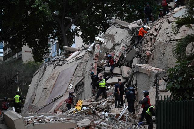 Rescuers search for victims in a collapsed building following an earthquake in Caracas on June 24, 2026. A magnitude 7.1 earthquake struck Venezuela on Wednesday, the United States Geological Survey (USGS) reported, triggering panic in Caracas, according to AFP journalists. The tremor, which was followed by several aftershocks, was also felt in Colombia. (Photo by Juan BARRETO / AFP)
