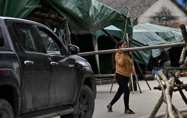 A woman lifts a barricade to allow a vehicle to pass at a roadblock set up by Indigenous people and local residents awaiting instructions from their leaders on whether roadblocks will resume or an agreement will be reached with the government, in Lauca Eñe, Cochabamba Department, Bolivia, on June 24, 2026. (Photo by MARTIN BERNETTI / AFP)