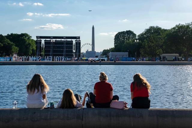 People wait at the base of the reflecting pool at the US Capitol for the fly over the National Mall during a kick-off celebration for the "Great American State Fair" on the National Mall in Washington, DC, June 24, 2026. The "Great American State Fair" will be held from June 25 to July 10, 2026, to celebrate the 250th anniversary of US independence. (Photo by Ken Cedeno / AFP)