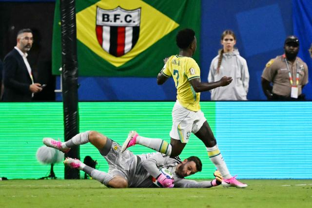 Scotland's goalkeeper #01 Angus Gunn catches the ball next to Brazil's forward #07 Vinicius Junior during the 2026 World Cup Group C football match between Scotland and Brazil at the Miami Stadium in Miami Gardens on June 24, 2026.  (Photo by CHANDAN KHANNA / AFP)